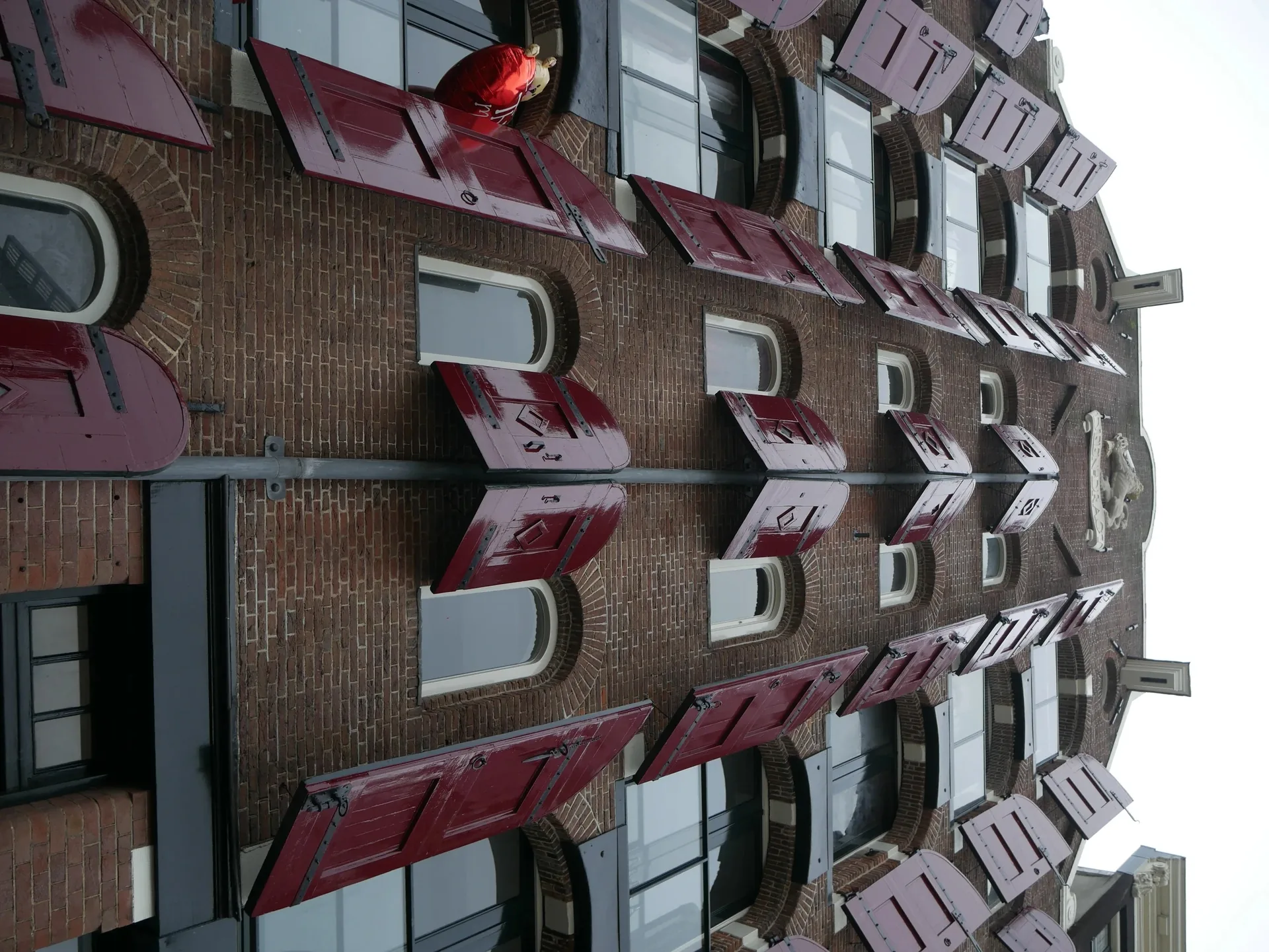 Façade de maison hollandaise en briques rouges avec volets rouges à Amsterdam