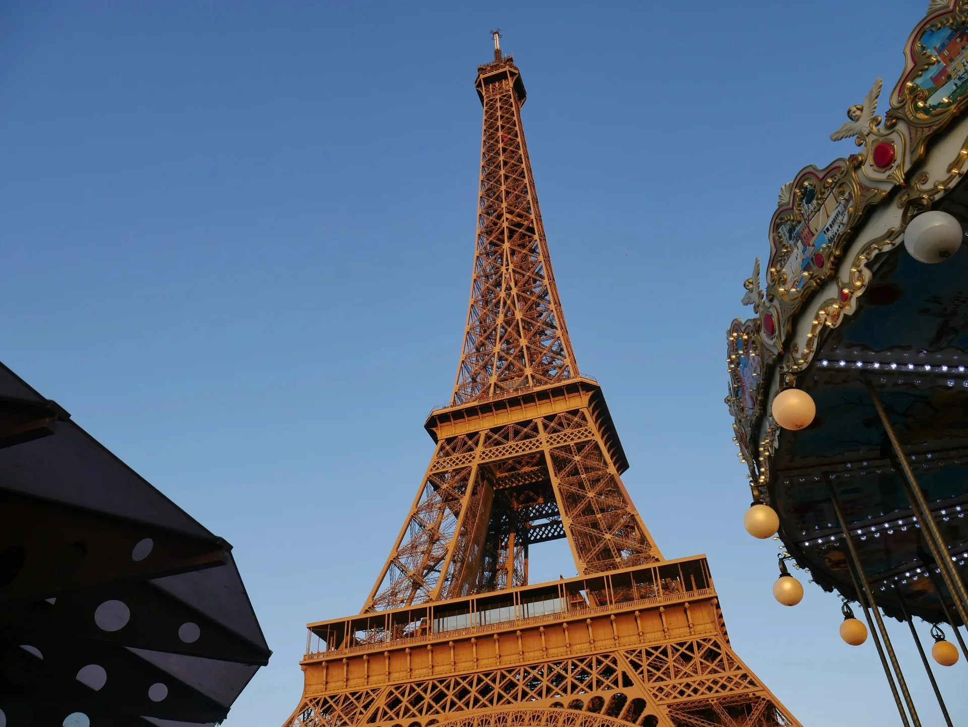 Tour Eiffel et carrousel parisien en lumière dorée sous ciel bleu